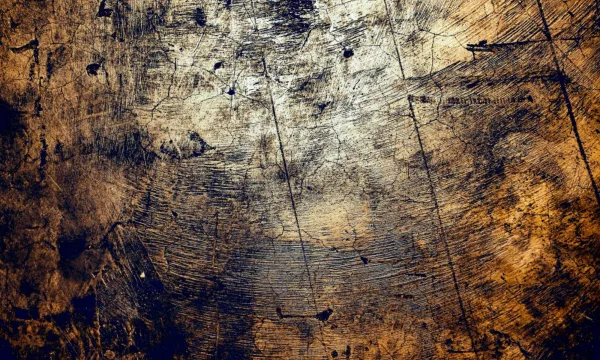 Close-up of a textured wooden surface with scratches and abstract patterns in dark and light tones.