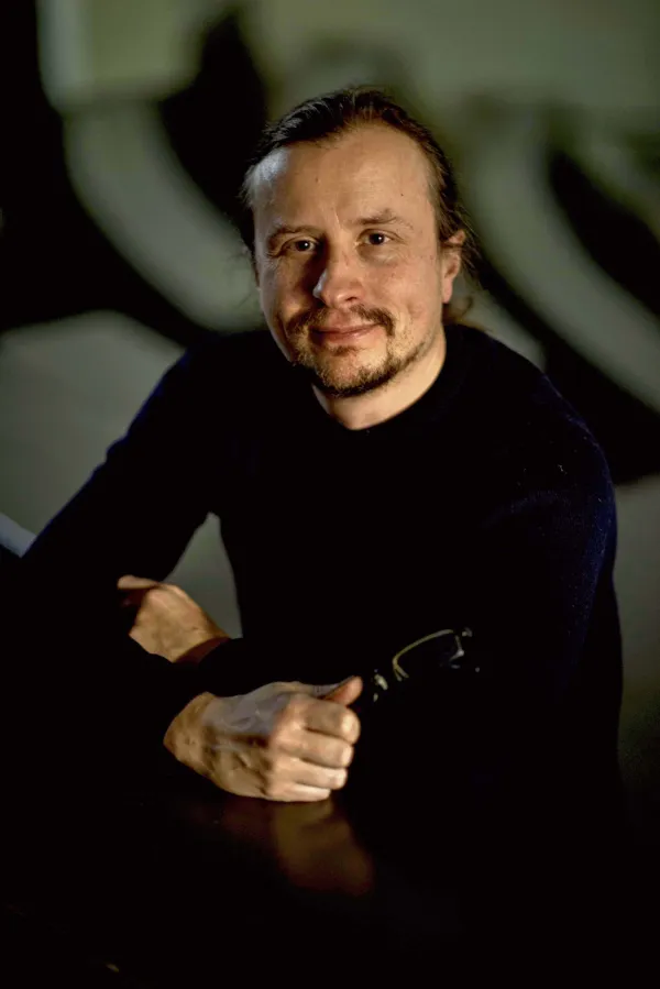 Otto Lappi. Photo by M. Verkasalo. Otto Lappi sitting at a table and holding his glasses in one hand.