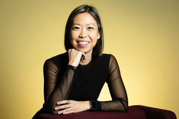 Corrie Tan. Photo by V. Somerpuro. Corrie Tan, smiling widely with her face resting against her hand.