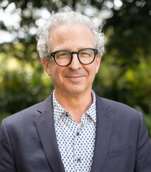 David Schlosberg wearing eyeglasses and a gray suit, smiling.