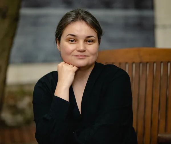 a woman wearing a black shirt, sitting on a chair, looking straight into the camera