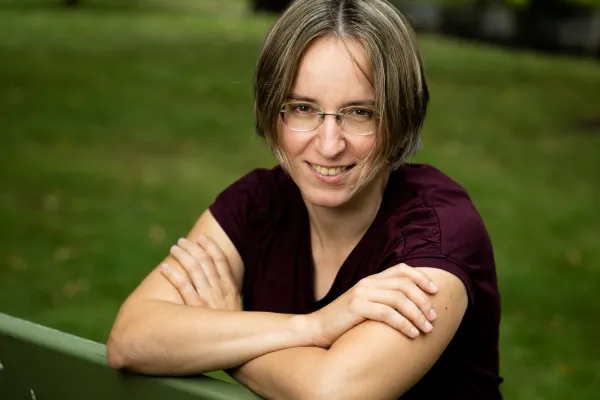 Lina Klymenko sitting on a park bench arms crossed, smiling.