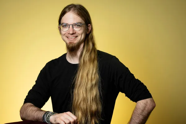 Stefan Dedio. Photo by V. Somerpuro. Stefan Dedio wearing eyeglasses and a black shirt, smiling widely.