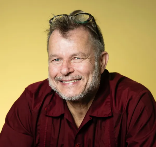 Teivo Teivainen. Photo by V. Somerpuro. Teivo Teivainen wearing a red button-up shirt, with eyeglasses resting on his forehead.