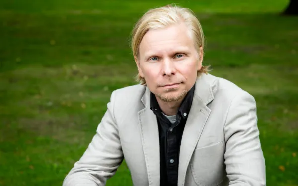Tero Toivanen sitting outside, wearing a light gray blazer.
