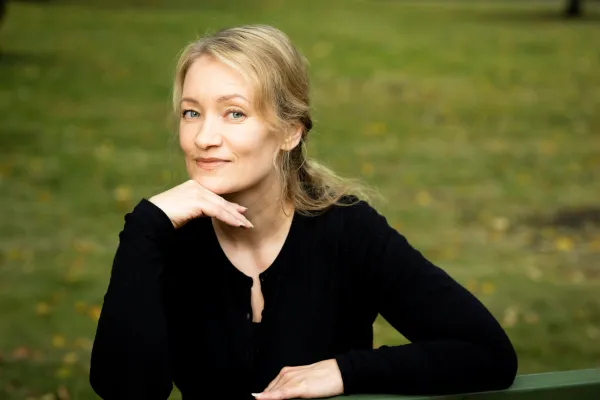 Satu Venäläinen. Photo by V. Somerpuro. Satu Venäläinen sitting on a bench with her face resting against her hand.