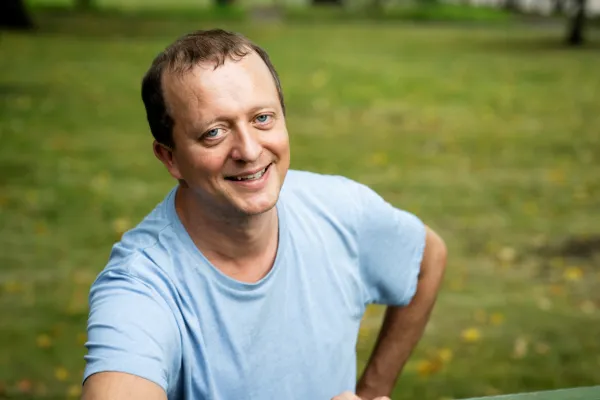 Janne Mattila. Photo by V. Somerpuro. Janne Mattila, wearing a blue t-shirt, smiling with one hand on his hip.