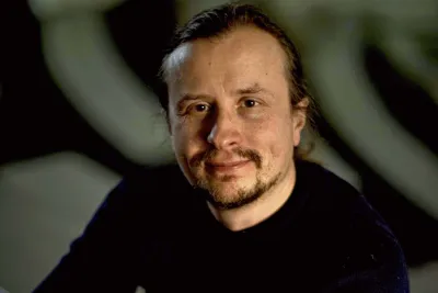 Otto Lappi. Photo by M. Verkasalo. Otto Lappi sitting at a table and holding his glasses in one hand.