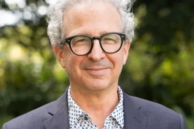 David Schlosberg wearing eyeglasses and a gray suit, smiling.