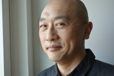 Kevin Toh wearing a black button-up shirt, smiling.