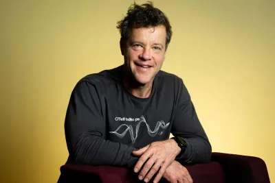 Kevin Durrheim leaning against a chair and smiling widely.