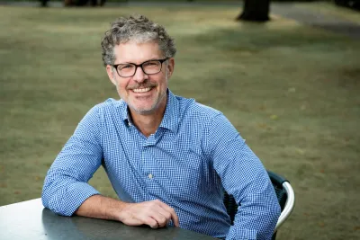 Charlie Kurth sitting outside, smiling widely.