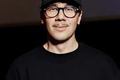 Headshot of Andriy wearing a black cap that says “Long Hugs” and a black T-shirt with Cyrillic text.