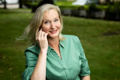 Nina Öhman wearing a green button-up shirt, resting face against hand.