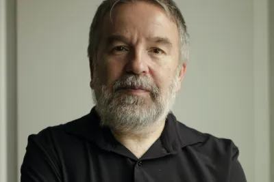 Oleg Lekmanov wearing a black button-up, standing hands crossed.