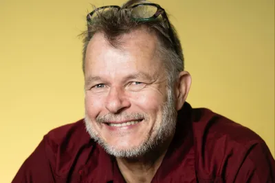Teivo Teivainen wearing a red button-up shirt, with eyeglasses resting on his forehead.