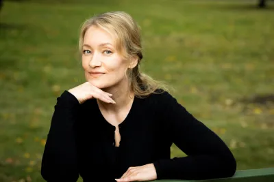 Satu Venäläinen sitting on a bench with her face resting against her hand.