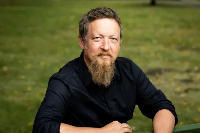 Kerkko Nordqvist wearing a black button-up shirt, smiling softly.