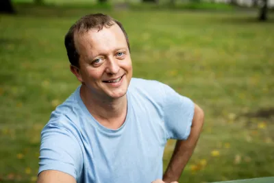 Janne Mattila, wearing a blue t-shirt, smiling with one hand on his hip.